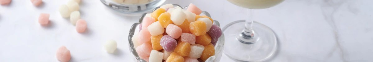 A top shot of colorful Mini Mochi placed in a glass against a white marble counter