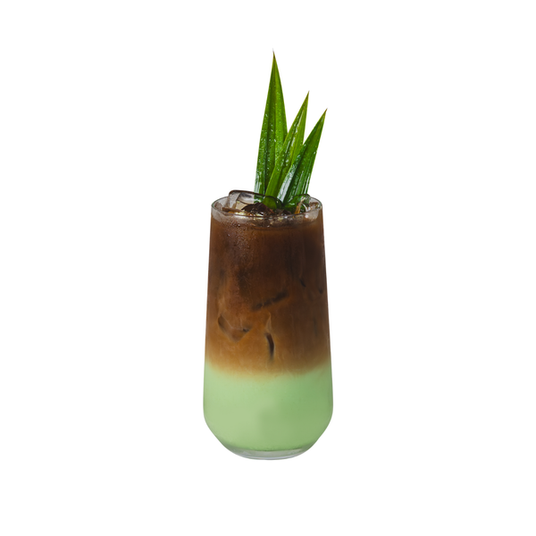 Two-toned drink in a glass with a green top and brown bottom, garnished with a leaf on a white background. view 3