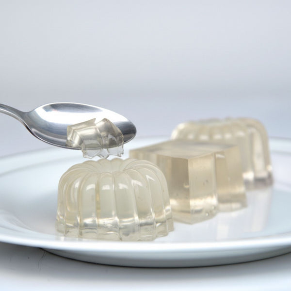 Plain Jelly positioned on a small white plate with a spoon lifting up a small chunk of jelly view 2
