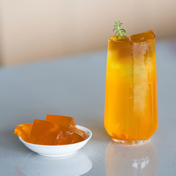 Peach Oolong tea with green tea jelly sitting on a counter, alongside a small plate of tea jelly view 4