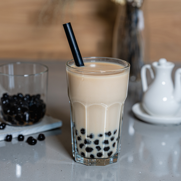 Glass of bubble tea with black tapioca pearls on a countertop. view 4
