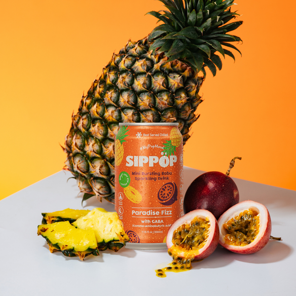 Sippop Paradise Fizz can with a pineapple and passion fruit on an orange background view 3