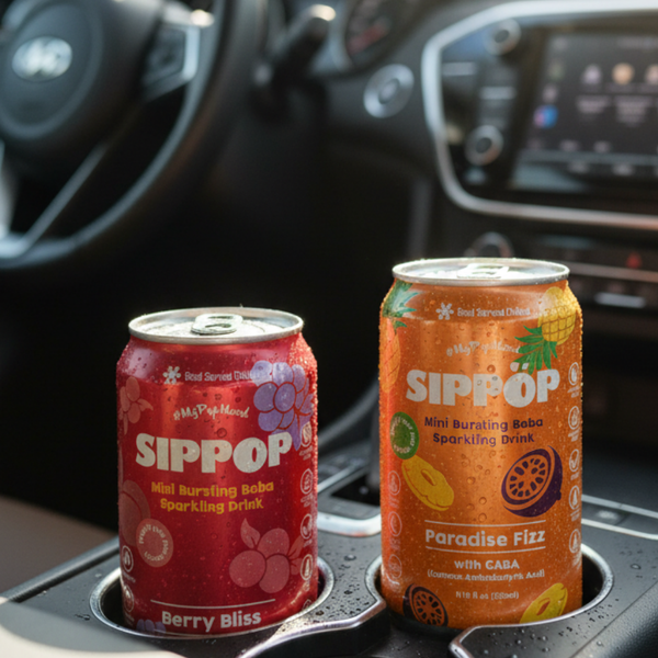 Two cans of Sippop drinks on a car cup holder with a car interior background. view 4